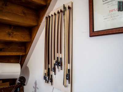 Ci guardiamo intorno. Appesi ai muri notiamo una fila di archi necessari per suonare lo strumento: sono costituiti da una bacchetta curvata di legno brasiliano (il pernambuco) e da un fascio di crini di cavallo bianco